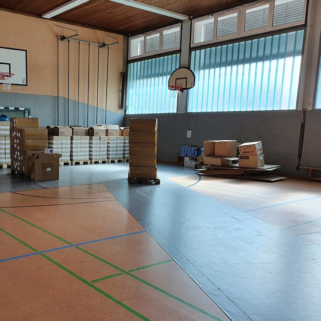 Paletten mit Selbsttests in einer Turnhalle.