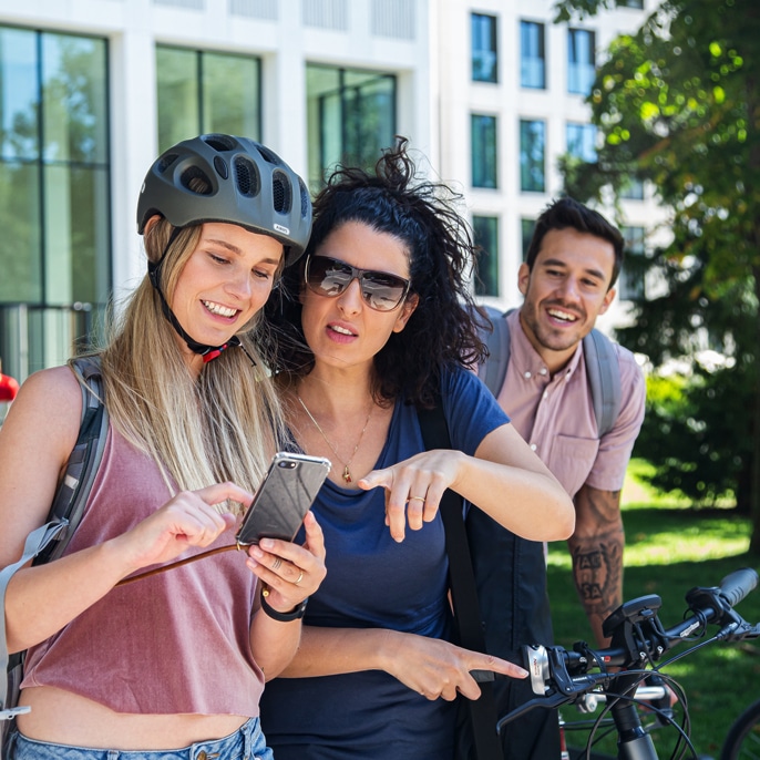 Zwei junge Frauen mit Fahrrad schauen auf ein Handy.