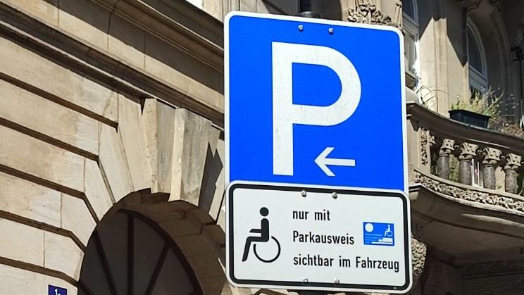 Verkehrszeichen 314 (P auf blauen Grund) mit Zusatzschild: Rollstuhlsymbol, mit Text: nur mit Parkausweis sichtbar im Fahrzeug.