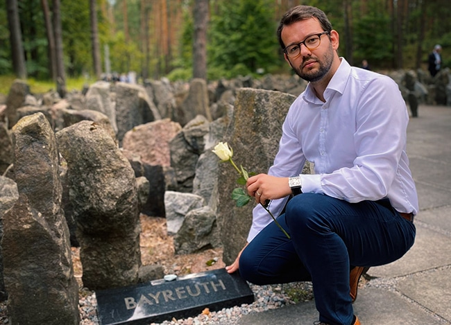 Bürgermeister Zippel mit Rose in der Hand berührt den Gedenkstein mit dem Logo der Stadt Bayreuth