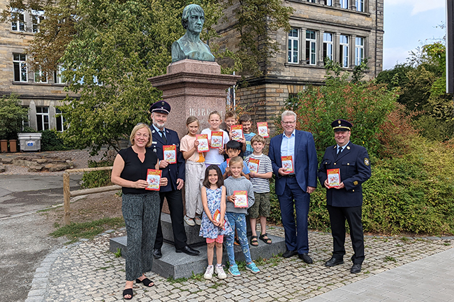 Menschen- und Kindergruppe vor dem Denkmal von J. Graser an der Graserschule