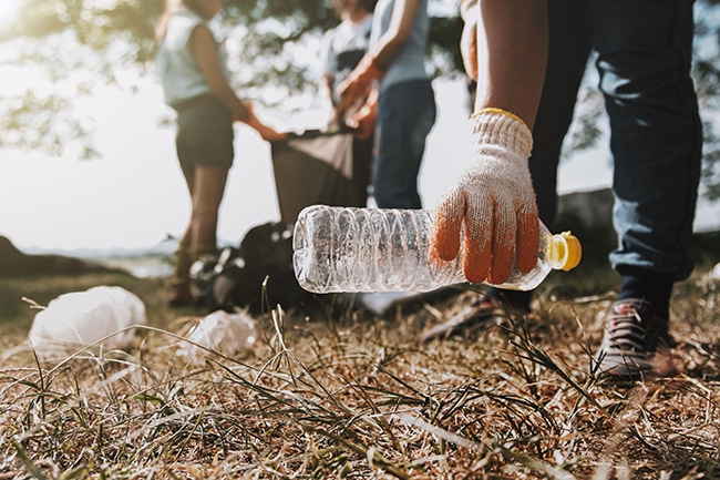 Eine Hand hebt gerade eine Plastikflasche auf.