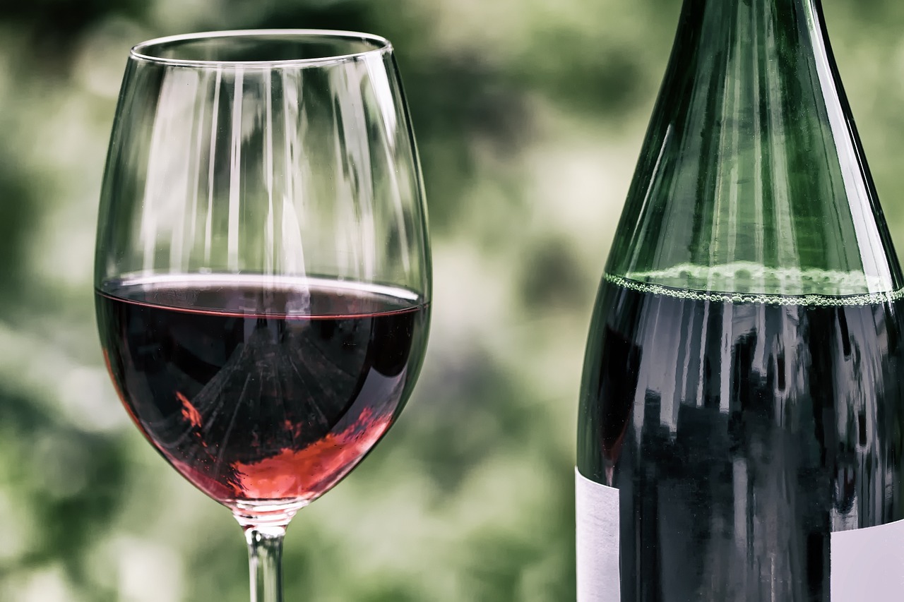 Ein mit Rotwein gefülltes Glas steht neben einer Weinflasche. | Foto: Pixabay