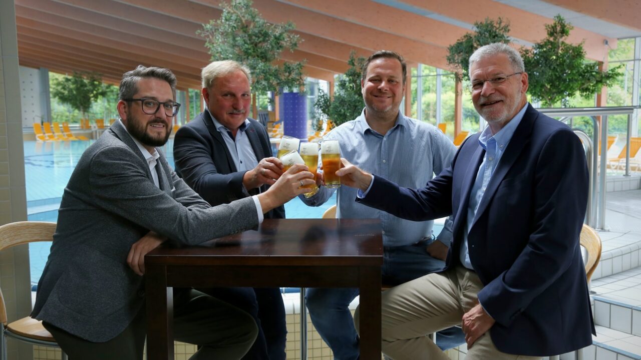 Vier Männer sitzen an einem Bistro-Tisch und stoßen mit ihren Getränken an. | Foto: Stadtwerke Bayreuth