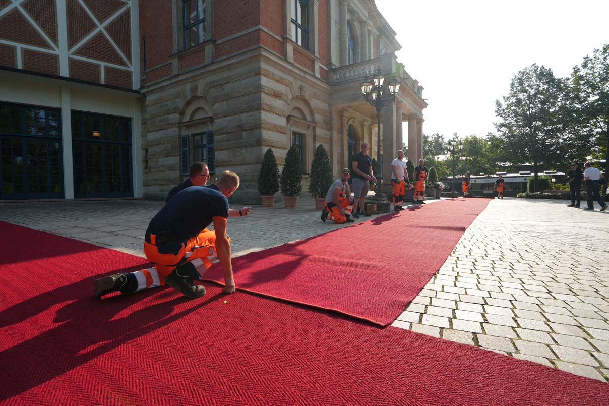 Mitarbeiter des Stadtbauhofs rollen dem roten Teppich vor dem Festspielhaus aus. | Foto: Stadt Bayreuth