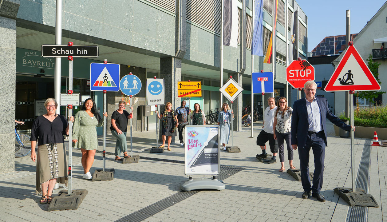 Mehrere Personen stehen vor dem Rathaus-Eingang an Verkehrsschildern mit Slogans. | Foto: Stadt Bayreuth