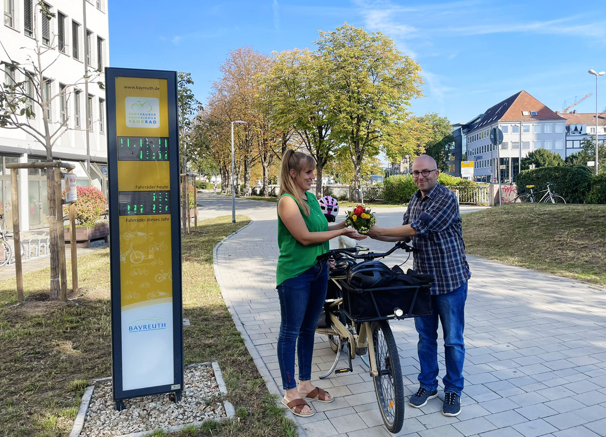 Eine Frau steht an ihrem Fahrrad und erhält von einem Mann einen Blumenstrauß. | Foto: Stadt Bayreuth