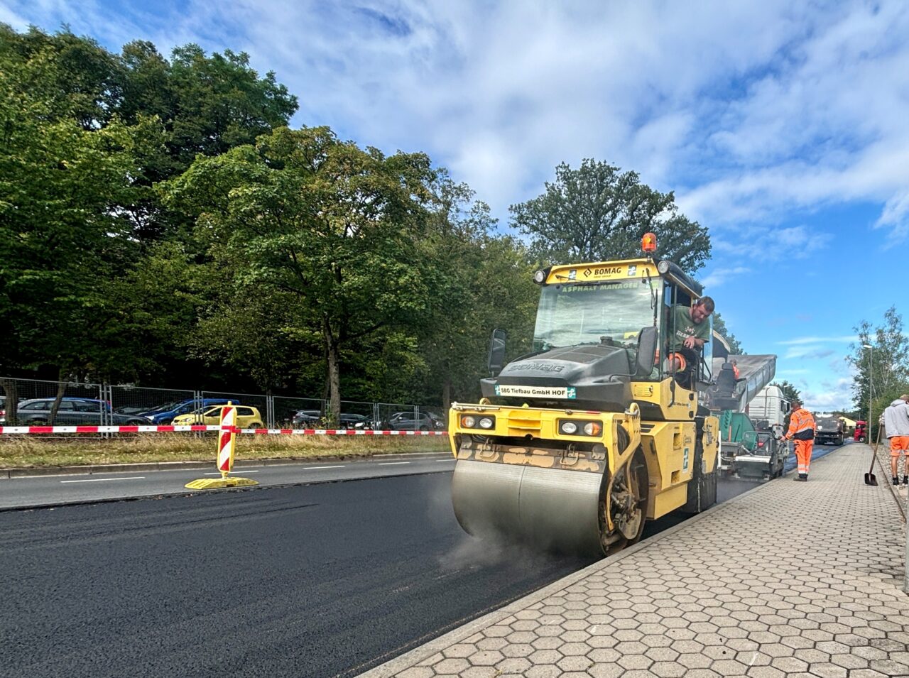 Eine Walze verdichtet eine frisch asphaltierte Straße