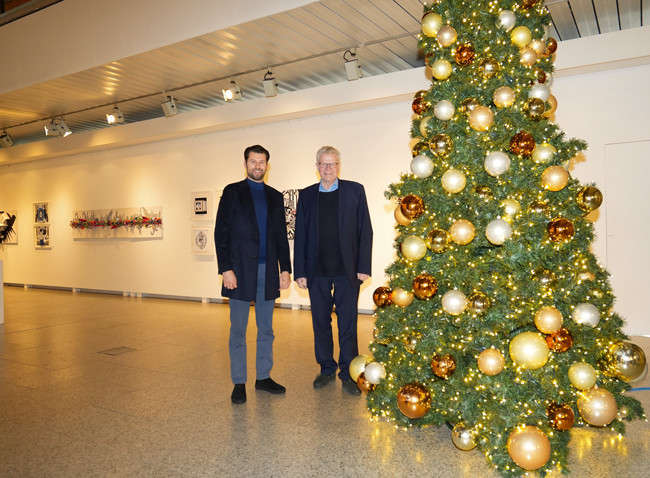 Zwei Männer stehen in einer Halle neben einem Weihnachtsbaum.