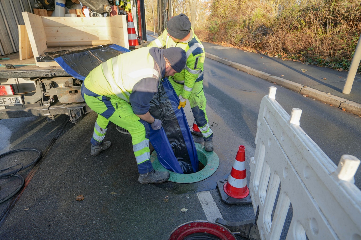 Die Mitarbeiter der von der Stadt Bayreuth beauftragten Sanierungsfirma ziehen den mit Glasfasern verstärkten Kunststoffschlauch in das Kanalrohr ein.