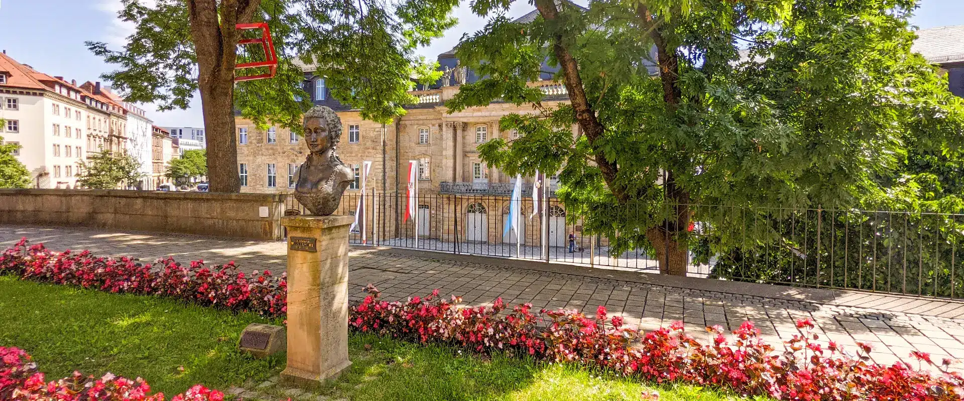 Skulptur von Markgräfin Wilhelmine in sommerlicher Umgebung mit Blumenbeten und Kunstobjekten