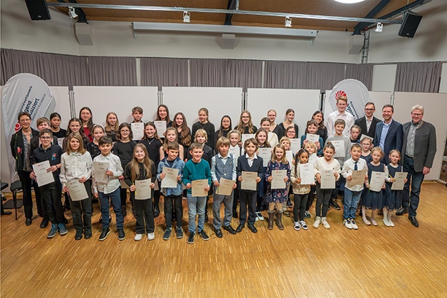 Die Preisträger/innen stehen nebeneinander und halten ihre Urkunden in der Hand.