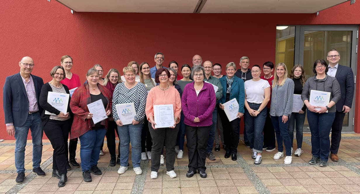 Eine Personengruppe steht mit Urkunden in den Händen vor einer roten Hauswand. | Foto: Stadt Bayreuth